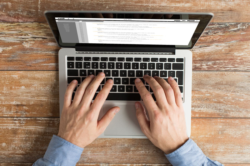 above view of person's hands typing on a laptop